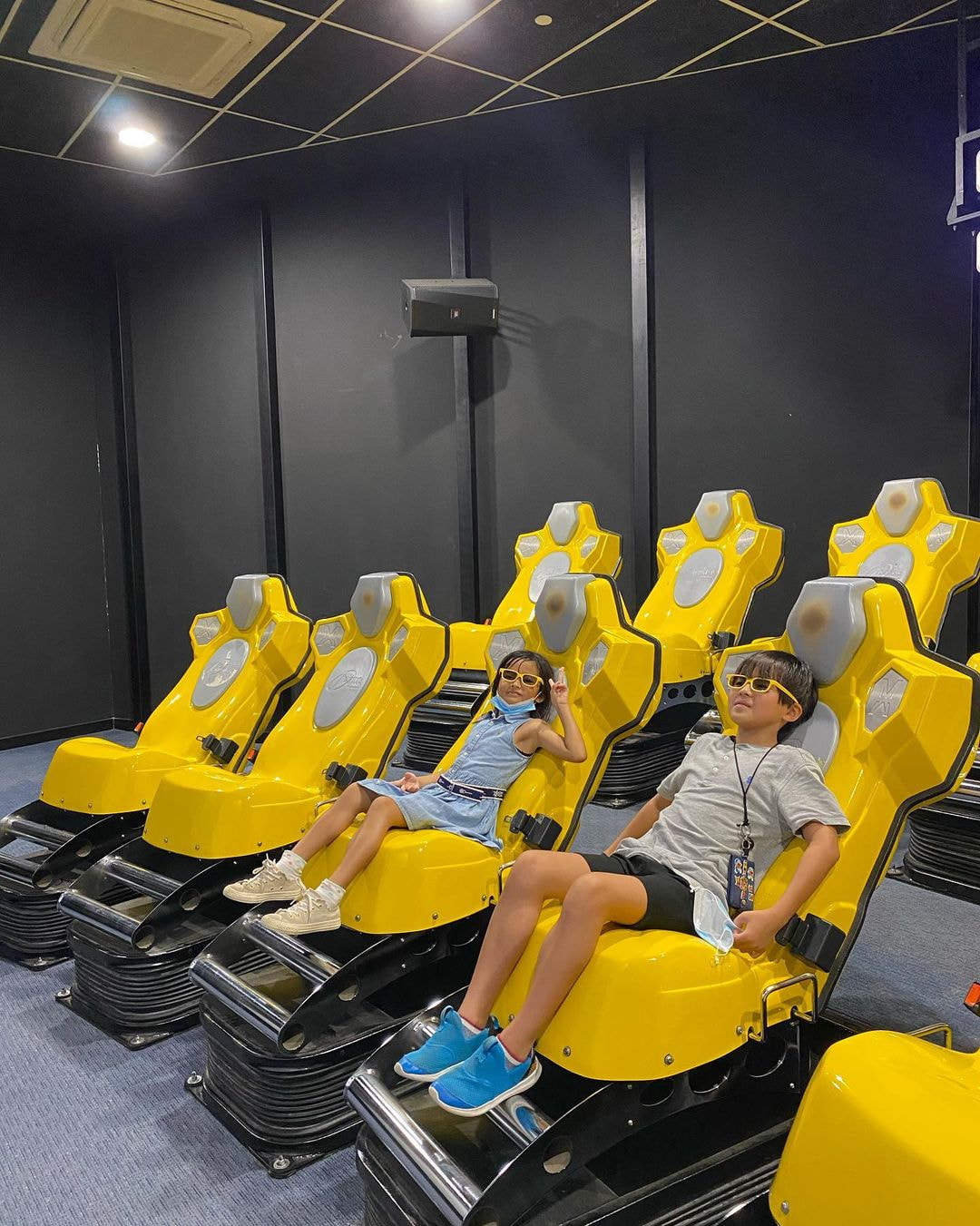 two kids on singapore discovery centre's xd theatre 4d cinema seats with special glasses